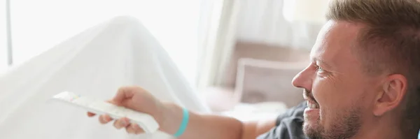 Jeune homme couché au lit avec télécommande — Photo