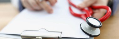 Elinde evrak ve kırmızı steteskop olan bir dosya tutan doktor.