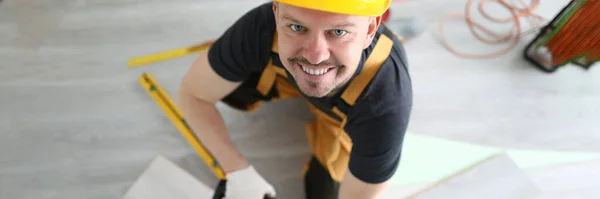 Carpenter in hard hat cutting laminate with electric saw top view — Stock Photo, Image