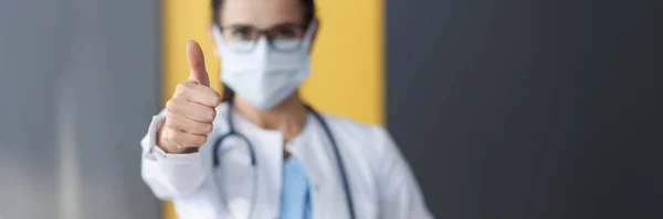 Vrouwelijke arts in beschermende medische masker tonen duim omhoog — Stockfoto