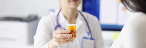 Arts geven pot van geneesmiddelen aan jonge vrouw in kliniek closeup — Stockfoto
