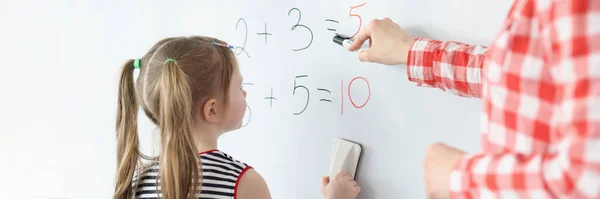 Gadis kecil dan guru memecahkan persamaan matematika di papan tulis — Stok Foto