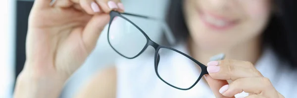 Ung kvinna håller svarta glasögon för syn i händerna — Stockfoto