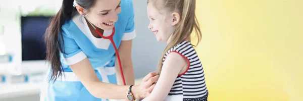 Pediatrician listening to lungs and heart of little girl in clinic — стоковое фото