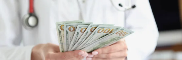 Dottore in possesso di un sacco di banconote dollari nelle sue mani in clinica primo piano — Foto Stock