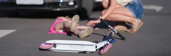 Skuter anak-anak tergeletak di latar belakang gadis kecil yang terluka dan pengemudi wanita menutup mobil — Stok Foto