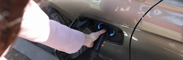 Kobieta wkładająca ładowarkę elektryczną w zbliżenie samochodu — Zdjęcie stockowe