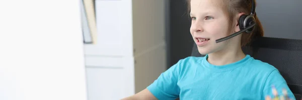 小さな女の子のヘッドフォンでマイクがコンピュータ画面の前に座って — ストック写真