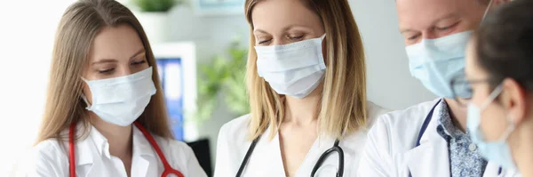 Groep artsen in beschermende medische maskers staan met documenten in hun handen in de kliniek — Stockfoto