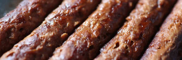 Closeup of grilled meaty appetizing fried sausages — Stock Photo, Image