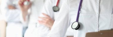 Boynunda steteskop olan bir grup doktor klinikte yakın plan çekimde duruyor.