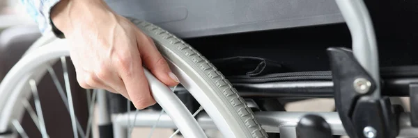 Behinderte Frau sitzt im Rollstuhl und hält sich an Rollstuhl fest — Stockfoto
