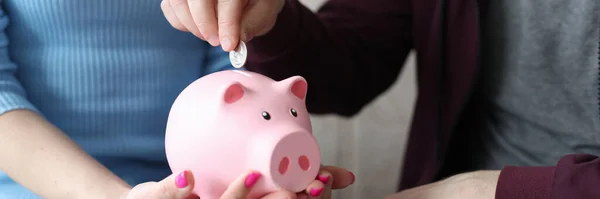 Man putting coin into pink piggy bank in hands of his wife closeup — Stock Photo, Image