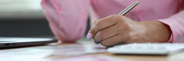 Kobieta trzyma długopis i robi notatki w dokumentach przy stole roboczym — Zdjęcie stockowe