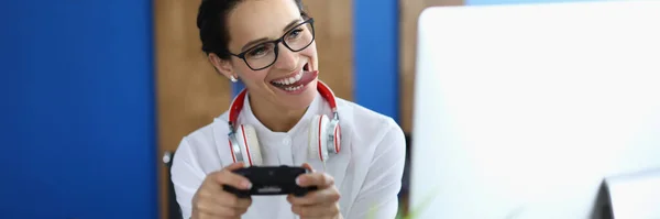 Mujer alegre sostiene el joystick juego en sus manos y juega juegos en línea en la oficina — Foto de Stock