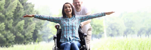Cara carrega mulher alegre em cadeira de rodas closeup — Fotografia de Stock