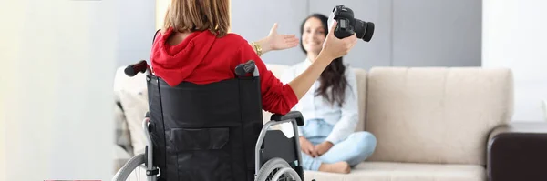 Жінка в інвалідному візку тримає камеру і фотографує модель — стокове фото