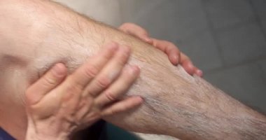 Adam ayaklarının derisine koruyucu nemlendirici sürüyor. 4K film.