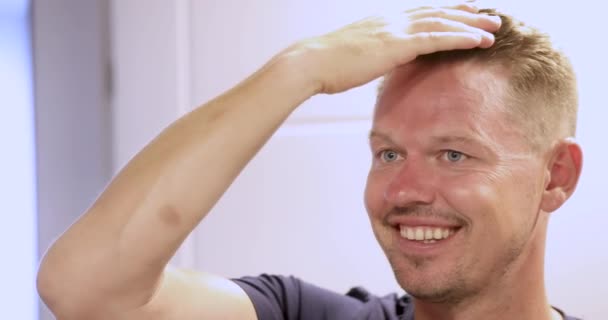 Feliz sonriente hombre mirando en el espejo y alisando su pelo 4k película — Vídeo de stock