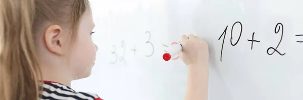 Little girl writes math examples on white board — Stock Photo, Image