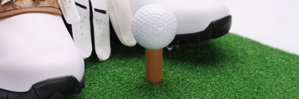 Eldivenli spor ayakkabıları ve yeşil çimlerin üzerinde uzanan golf topu. — Stok fotoğraf