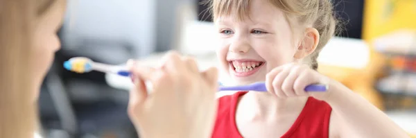 Menina é ensinada a escovar adequadamente os dentes com escova de dentes — Fotografia de Stock