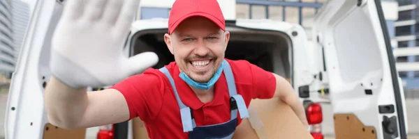 Sorrindo mensageiro masculino segurando grande caixa de papelão no fundo do carro — Fotografia de Stock