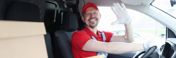 Man chauffeur koerier in cabine van auto zwaaien zijn hand in groet — Stockfoto