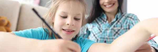 Kleines Mädchen zeichnet mit Bleistift auf Hintergrund sitzende Frau — Stockfoto