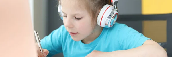 Kulaklıklı kız not defterine not alıyor. Masadaki dizüstü bilgisayar. — Stok fotoğraf