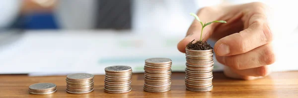 Before businessman stands pyramid of coins in ascending order on last pyramid