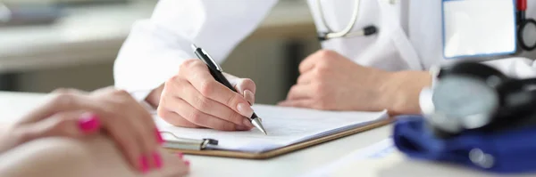 Ręce lekarza piszącego w karcie pacjenta — Zdjęcie stockowe