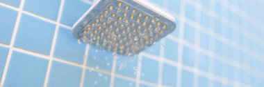 Duvara monte edilmiş krom duş mavi karoların üzerinde su damlaları ile