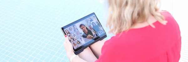 Junge Frau hält Online-Business-Konferenz per Tablet ab, während sie am Beckenrand sitzt — Stockfoto