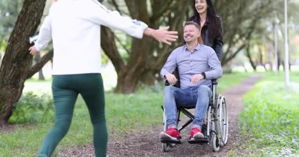 Young woman hugs happy man in a wheelchair on walk in park 4k movie — Stok Video