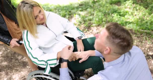 Adam, tekerlekli sandalyedeki genç kadını 4K filmle teselli ediyor. — Stok video