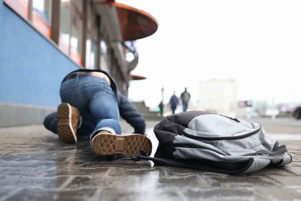 Man with backpack lying on slippery sidewalk after fall closeup — Stok Foto