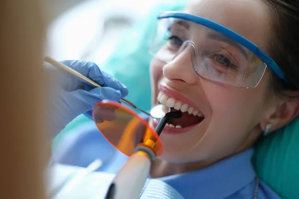 Orvos fogorvos kezelése fogak segítségével LED gyógyító fény gép klinika közelkép — Stock Fotó