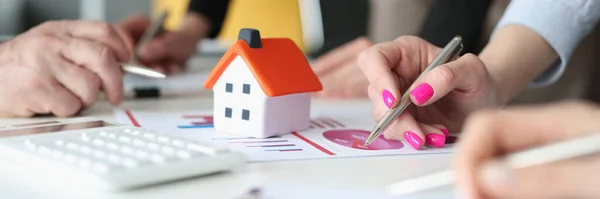 Hands of employees with pens and business charts and small house on table — Foto de Stock