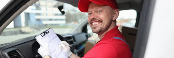 Courier man filling out documents on clipboard in car