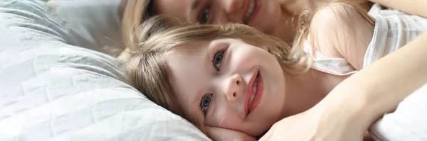 Mamá y niña acostadas en la cama y abrazadas —  Fotos de Stock