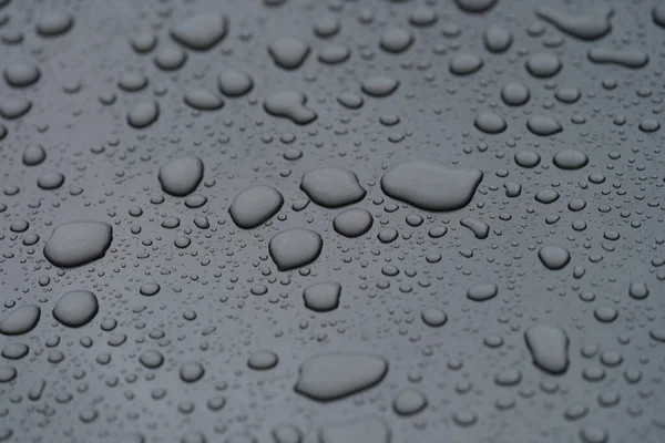 Closeup of raindrops on black hood of car background — Stock Photo, Image