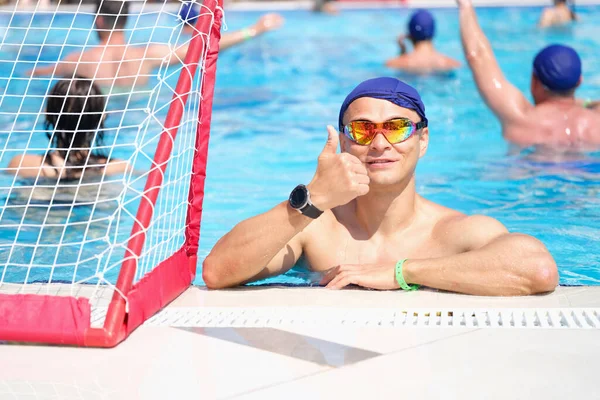 Νεαρός άνδρας με γυαλιά και καπάκια που δείχνει τον αντίχειρα στην πισίνα — Φωτογραφία Αρχείου