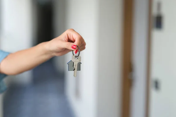 Mano femenina con manicura roja sosteniendo las llaves de la casa de cerca —  Fotos de Stock