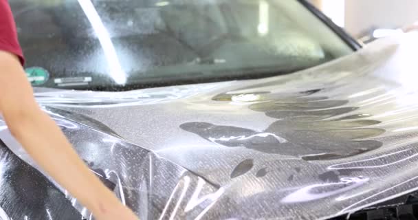 Человек-ремонтник обертывает защитную виниловую пленку над автомобилем 4К фильма — стоковое видео
