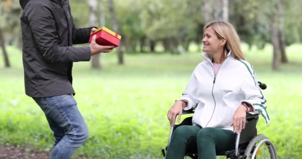 Junger Mann beschenkt behinderte Frau im Rollstuhl in Park 4k movie — Stockvideo