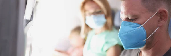 Junge Familie fliegt mit medizinischer Schutzmaske im Flugzeug — Stockfoto