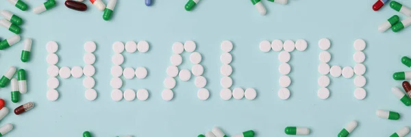 Palavra de saúde é colocado para fora de pílulas brancas no fundo de cápsulas multicoloridas closeup fundo — Fotografia de Stock