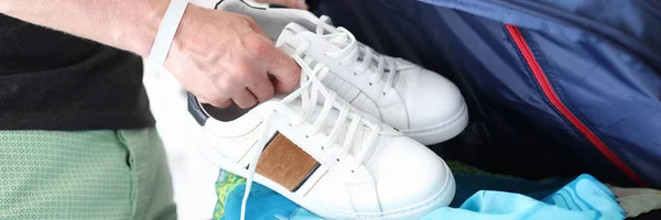 Ο άνθρωπος βάζει λευκά αθλητικά παπούτσια στη βαλίτσα με ρούχα closeup — Φωτογραφία Αρχείου