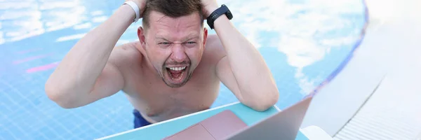 Ο άνθρωπος κολυμπάει στην πισίνα και σκίζει τα μαλλιά του μπροστά στην οθόνη του φορητού υπολογιστή — Φωτογραφία Αρχείου